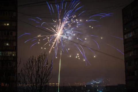 Night salute. Explosion lines of different colors. Outbreaks between houses. Фото