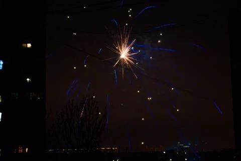 Night salute. Explosion lines of different colors. Outbreaks between houses. 스톡 사진