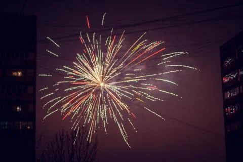 Night salute. Explosion lines of different colors. Outbreaks between houses. Фото