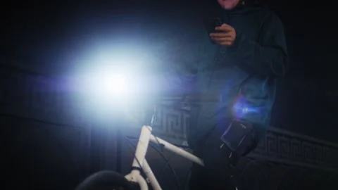 Night Scene of Cyclist with Helmet Using Phone and Riding Away 库存影片 345708946