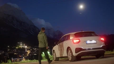 Night scene of man getting into white car in Cortina Dolomites Italy Video stock 320254638