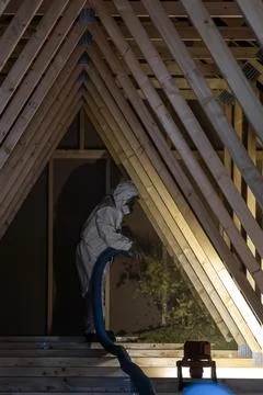 Night shift insulation in attic with A frame rafters and gusset plates Stock Photos
