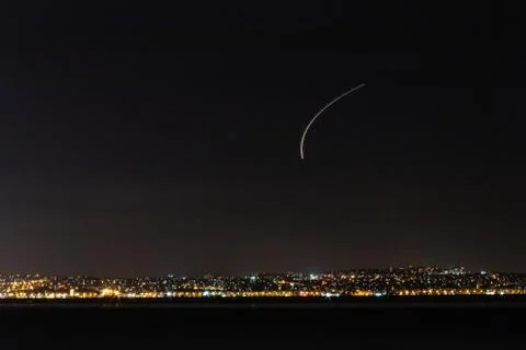 Night shoot from distant coast - plane made white line at sky Stock Photos