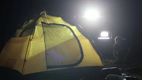 Night shot of two mans erecting tent in ligh from expeditionary SUV. Stock Footage 75952611