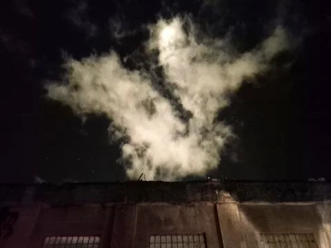 Night sky cloud and dramatic smoke plume over city buildings Foto stock