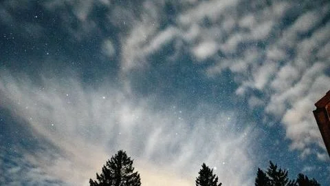 Night sky filled with an array of fluffy clouds illuminated by starlight. Foto stock