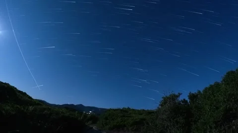 Night sky time lapse featuring star trails and satellite movement over a dark Video stock 325711842