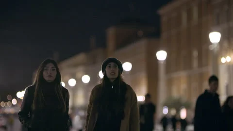 At night in St Peter's Square, two religious Italian women walk along the street Stock Footage 199458433