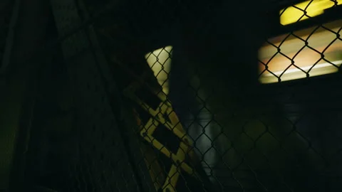 Night subway train passing across Manhattan Bridge behind a metal chain-link Video stock 322552228