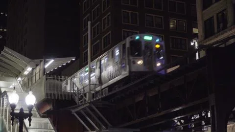 Night time exterior of loop train passing through elevated station on tracks  Stock Photos