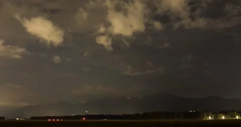 Night time lapse of clouds and stars moving over farming field Stock Footage 137449347