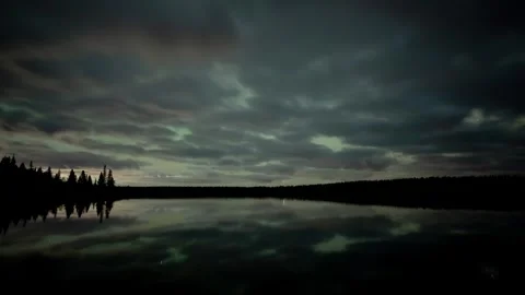 Night, time lapse at a large very calm lake with scattered clouds and stars Stock Footage 261300433