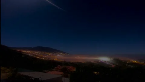 Night time lapse with a mountain in the background and clouds passing Stock Footage 148450952