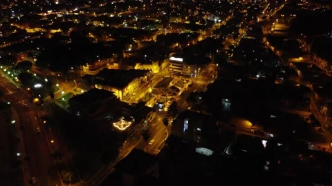 Night time lights shine through a city as drone flies backwards and Stock Footage 232682177