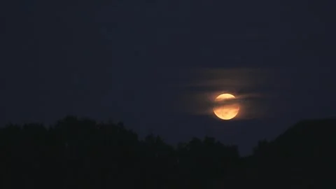 Night Timelapse of super moon rising in the sky behind clouds 库存影片 250029436