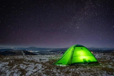 Night at the top of the mountain in a tent in winter against the background o Stock Photos
