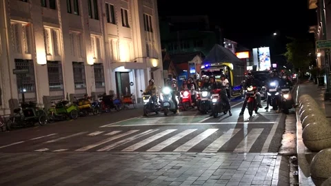 Night traffic at a city intersection with a row of motorbikes stopped at a red Stock Footage 336988595