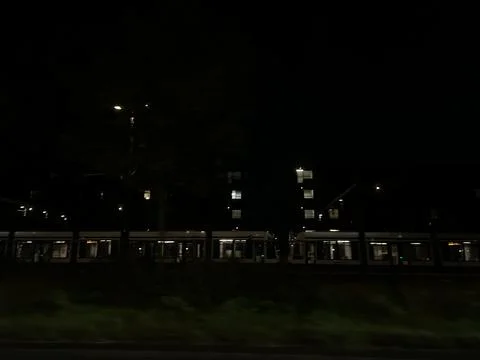 Night train station platform beside illuminated office building facade with Stock Photos