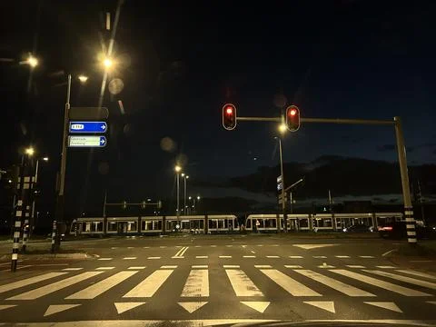 Night tram stop intersection with red traffic lights, illuminated direction Stock Photos
