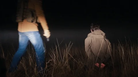 At night, an unknown person kills another with a gun. Stock Footage 124785139