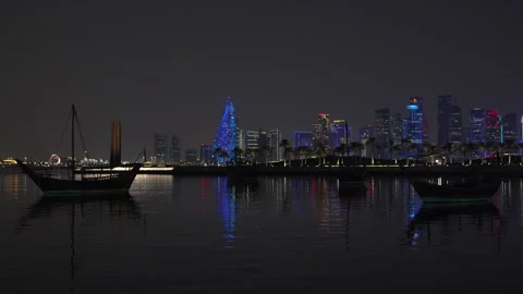 Night view of Doha's illuminated West Bay skyline across the bay behind MIA park Stock Footage 344874614