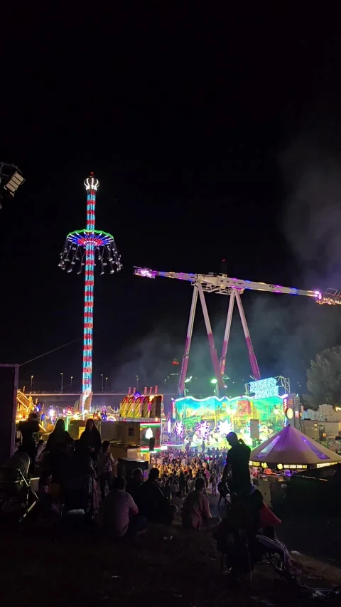 Night View of a Fairground with Tall Thrill Rides and Crowds Vídeo Stock 341628767