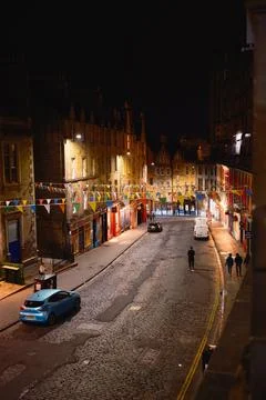 Night view of historic Edinburgh street with bunting, lights, and pedestrians Stock Photos