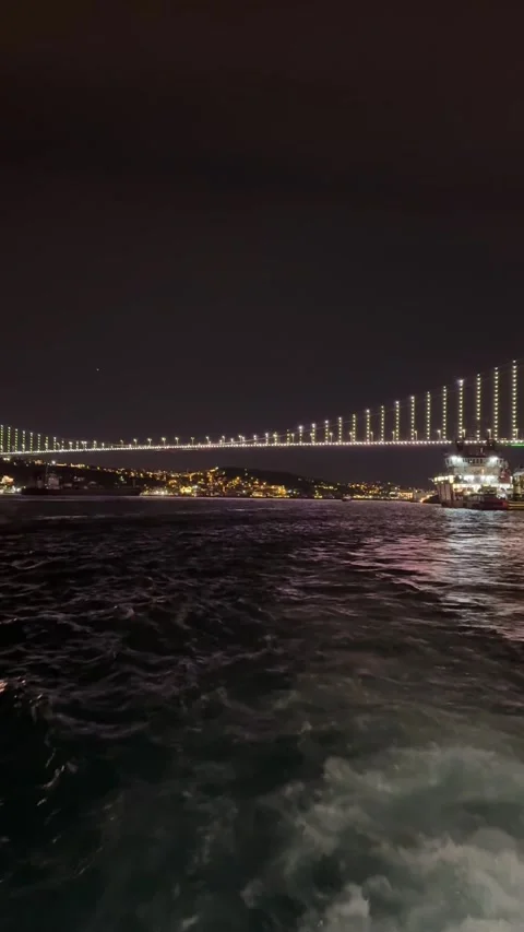 Night view of the illuminated Bosphorus Bridge from a moving boat, with water 库存影片 340897580