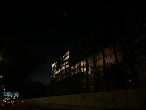 Night view of modern office skyscraper facade with illuminated window grid Stock Photos