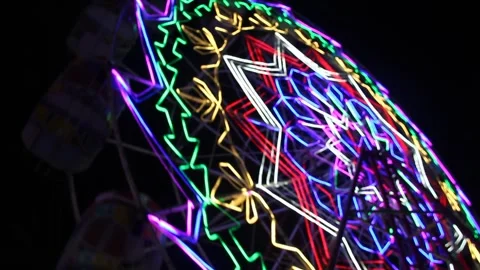 Night view of a moving Ferris wheel decorated with bright colorful neon lights Stock Footage 308618639