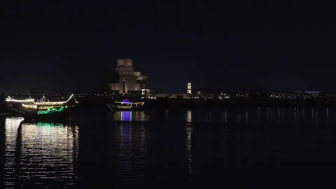 Night view of Museum of Islamic Art with traditional Qatari dhow boats sailing. Stock Footage 332709567