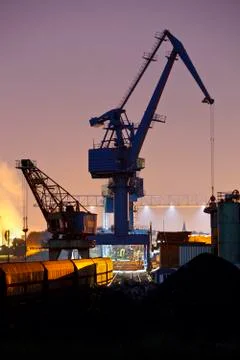 Night view of railroad tracks, a train and a tall crane in a coal harbor. Stock Photos