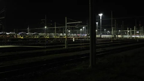 Night view of railway yard with freight train carrying new cars under bright ind Stock Footage 319243121