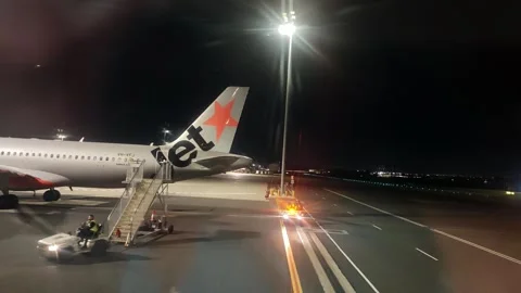 Night view of a team of ground crew working on a Jetstar plane Vidéo 338209552