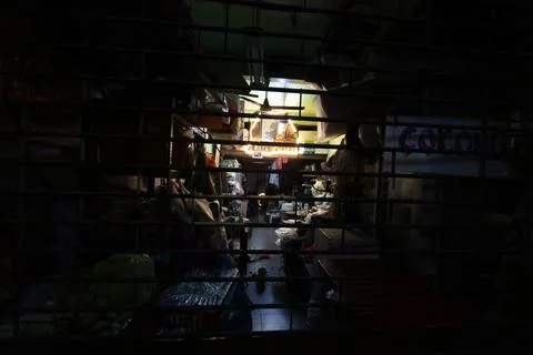 Night view through bars into a small shop with illuminated goods Stock Photos
