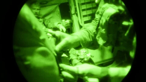 Night vision imagery of jumpmaster checking airman's parachute Stock Footage 120121192
