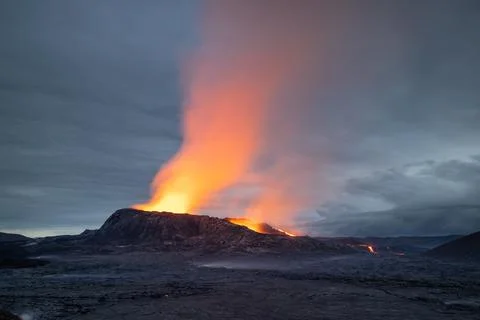 Night volcanic eruption. Fresh hot lava, flames and poisonous gases visible. Stock Photos