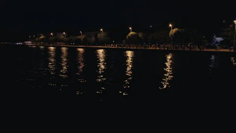 Night waterfront reflections along illuminated promenade Vídeo Stock 340623627