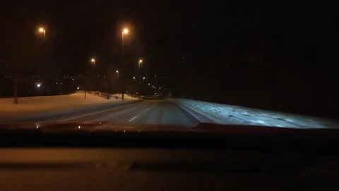 Night winter driving through snowy city street with traffic lights Stock Footage 329536546