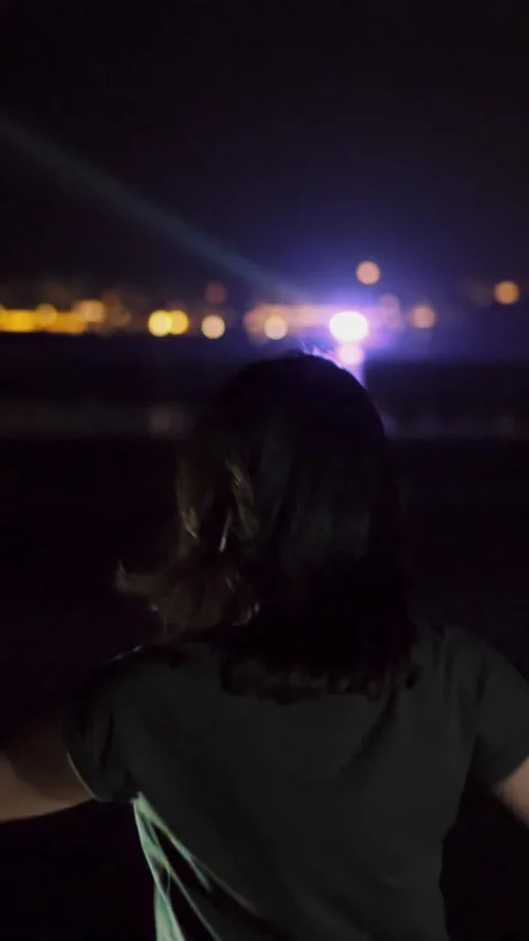 Night, a woman is dancing, view from the back. against the lights of the glowing Stock Footage 310563653