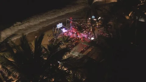 Nighttime beach gathering features music and dancing under palm trees Stock Footage 297929261