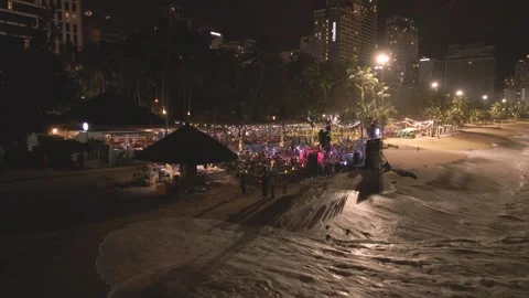 Nighttime beach party attracts crowds with vibrant lights and lively Stock Footage 297929304