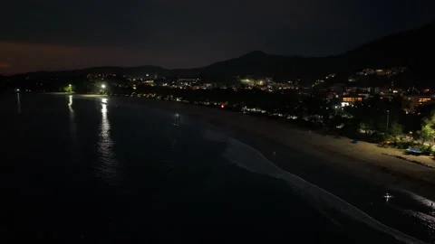 Nighttime beach view with illuminated shoreline and distant mountains in Video stock 342332881