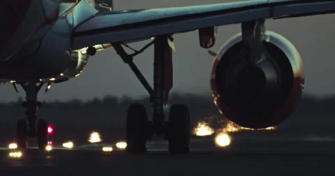 Nighttime Close-Up of Aircraft Wheels Rolling on Lit Runway Stock Footage 292260093