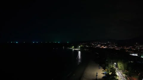 Nighttime coastal view with illuminated beach and city lights reflecting on Stockbeeldmateriaal 342332557