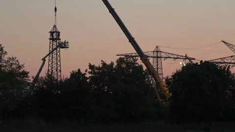 Nighttime construction work on a decommissioned power pole using a large crane. 库存影片 341871613