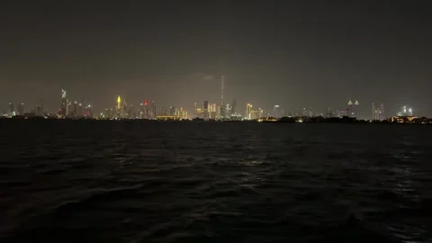 Nighttime Dubai with skyscraper lights, viewed from a ship sailing on the sea Video stock 303360536