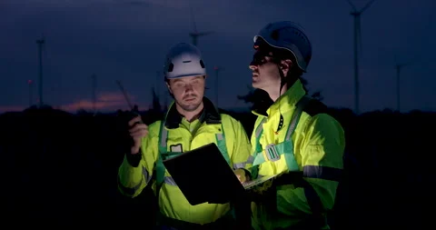 Nighttime engineers checking wind turbine operation using laptop and radio Stock Footage 328697516