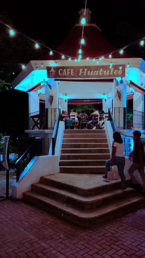 Nighttime exterior of Cafe Huatulco with string lights and illuminated entrance Stock Footage 343927019