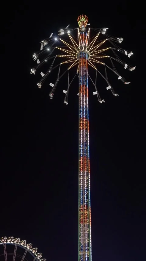 Nighttime illuminated swing with rotating canopy, giant glowing amusement tower Stock Footage 320138362